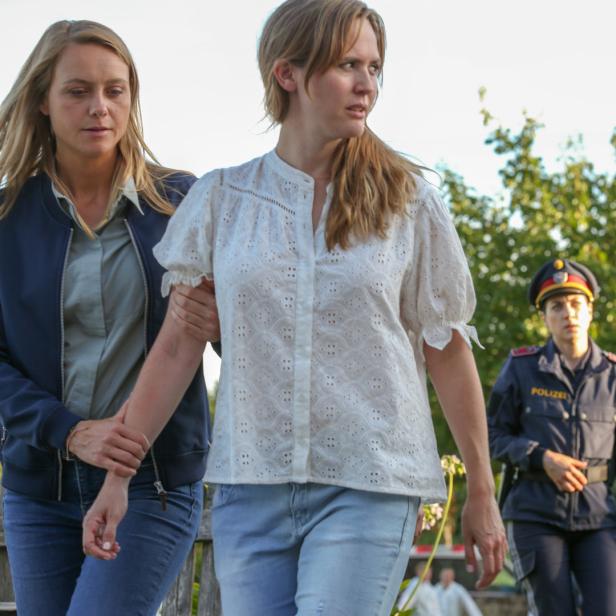 Zwei Frauen werden von einem Mann und einer Polizistin begleitet.