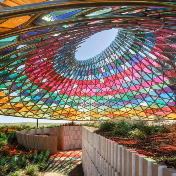 Ein farbenfroher Pavillon mit einem Dach aus Buntglas und einer spiralförmigen Öffnung zum Himmel.