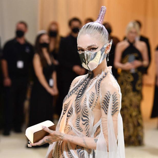 Grimes trägt eine futuristische Maske und ein transparentes Kleid.