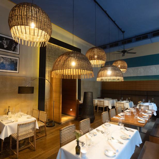 Ein elegantes Restaurant mit gedeckten Tischen und auffälligen Korbleuchten.