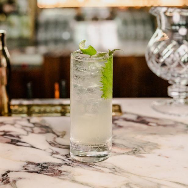 Ein erfrischender Cocktail mit Eis und Limette auf einer Marmorbar.