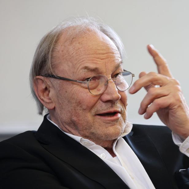 Ein älterer Mann mit Brille gestikuliert mit erhobenem Zeigefinger.