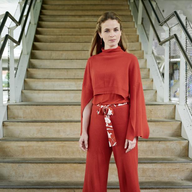 Eine Frau in roter Kleidung steht auf einer Treppe im Freien.