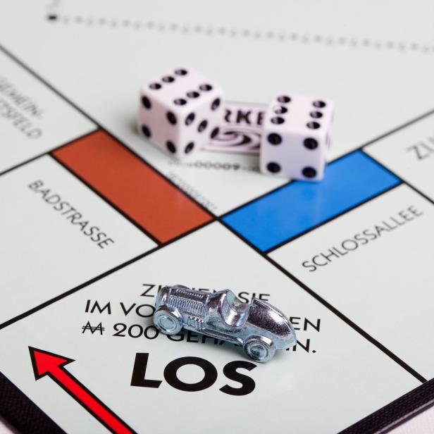 Ein Monopoly-Spielbrett mit Spielfigur und Würfeln auf dem Feld „Los“.