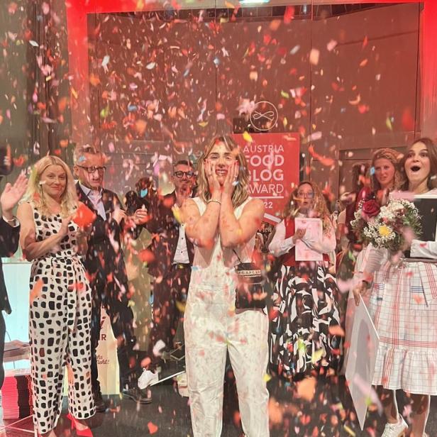 Eine Frau freut sich über den „Austria Food Blog Award“ unter Konfettiregen.