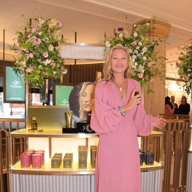 Kate Moss posiert vor einem Regal mit „Cosmoss“-Produkten.