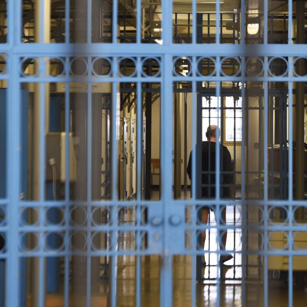 Ein Mann steht hinter Gittern im Gefängnis