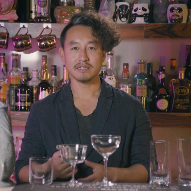 Ein Barkeeper steht hinter einer Bar mit verschiedenen Gläsern und Spirituosen.