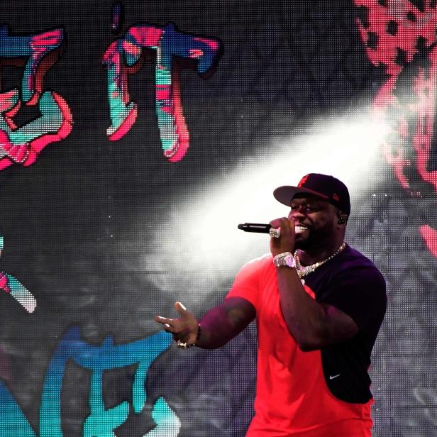 50 Cent tritt vor einer Leinwand mit dem Schriftzug „Get It Or“ auf.
