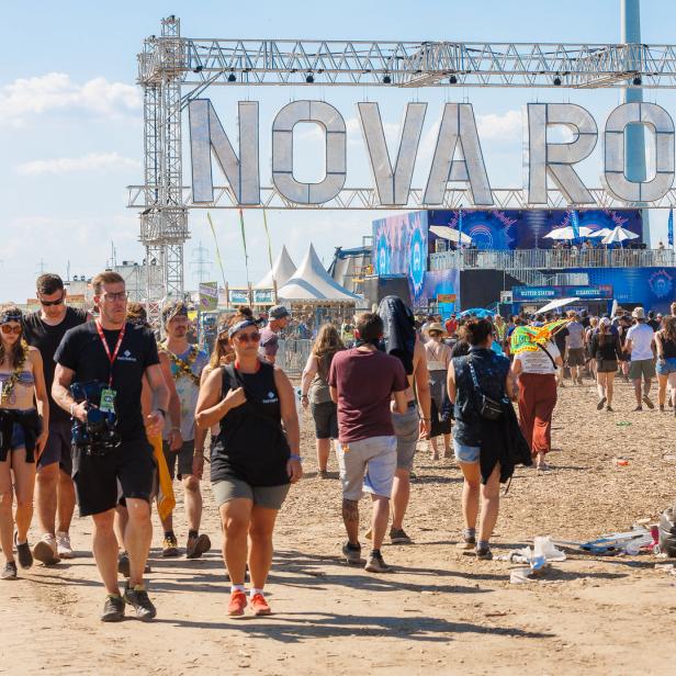 Besucher strömen zum Nova Rock Festival unter einem großen „Nova Rock“-Schild hindurch.
