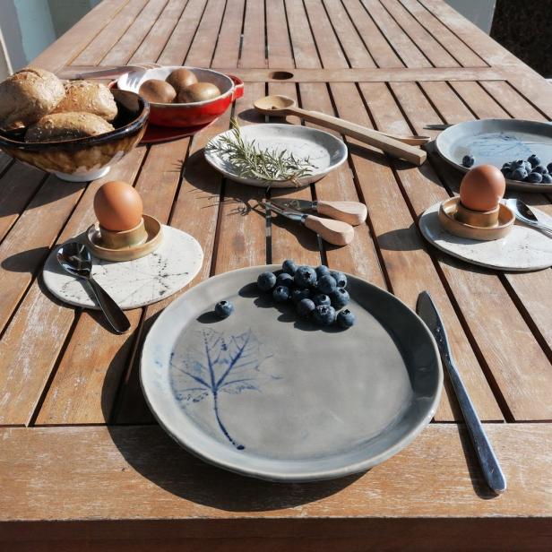Ein gedeckter Frühstückstisch mit Eiern, Brötchen und Blaubeeren im Freien.