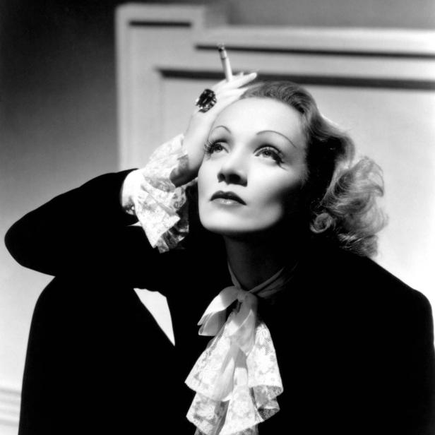 Marlene Dietrich mit Zigarette in der Hand, den Blick nach oben gerichtet.