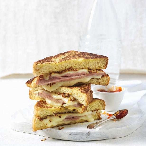 Ein Stapel aus drei French-Toast-Sandwiches mit Schinken, Käse und Senf.