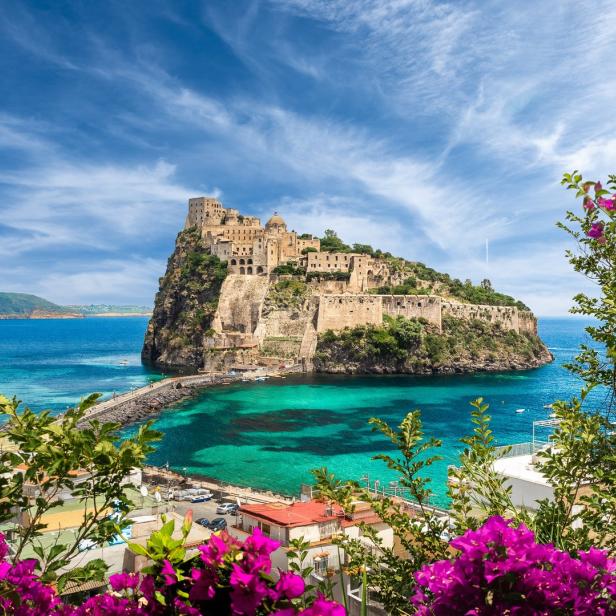 Das Castello Aragonese thront auf einer Felseninsel vor Ischia, verbunden durch einen Steg.