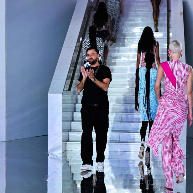 Ein Mann klatscht Beifall, während Models eine Treppe bei einer Modenschau hinaufgehen.