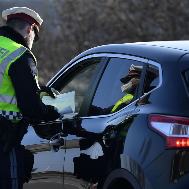 Ein Polizist kontrolliert die Papiere eines Autofahrers in einem schwarzen Nissan Qashqai.