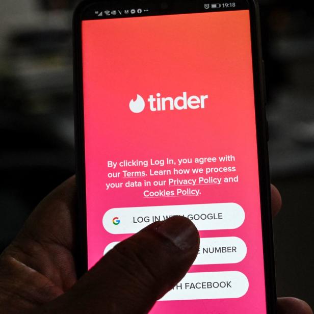 Ein Smartphone zeigt den Anmeldebildschirm der Dating-App Tinder.