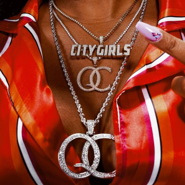 Nahaufnahme einer Person mit mehreren Halsketten, darunter eine mit der Aufschrift „City Girls“.