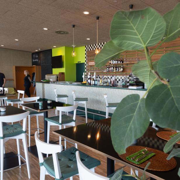 Einblick in ein modernes Restaurant mit Tischen, Stühlen und einer Bar.