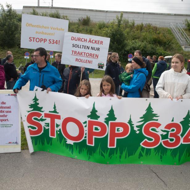 Demonstrierende mit Protestplakaten gegen die S34 und für den Ausbau des öffentlichen Verkehrs, einige Kinder vorn.
