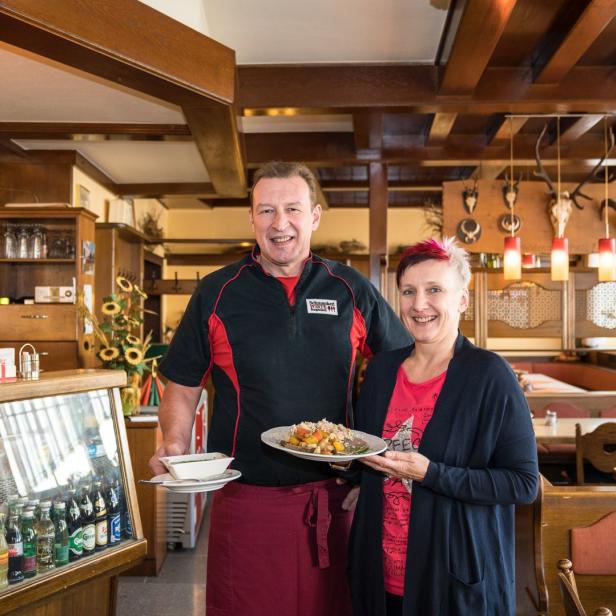 Ein Mann und eine Frau vom Gasthof Hutter präsentieren Speisen.