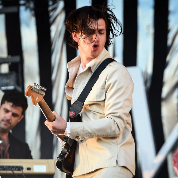 Alex Turner von den Arctic Monkeys spielt Gitarre auf einer Bühne.