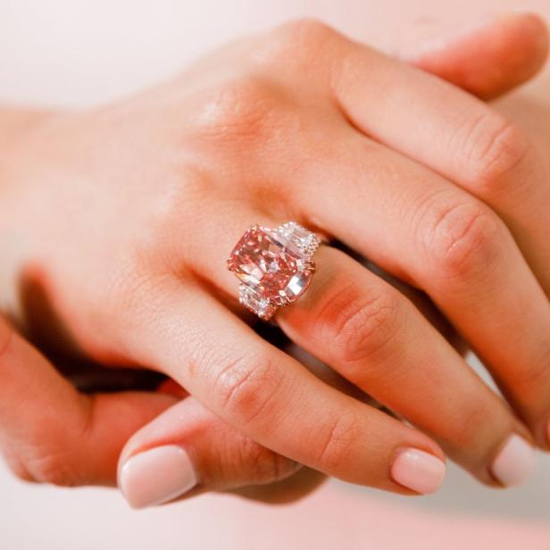 Die Hand einer Person mit einem großen rosafarbenen Diamantring.