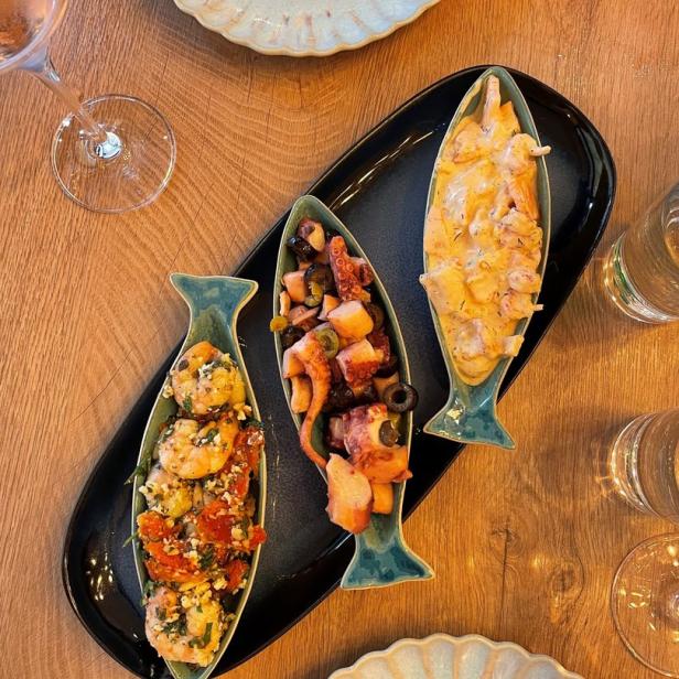 Drei Fischschalen mit Meeresfrüchtesalat auf einem Tisch angerichtet.