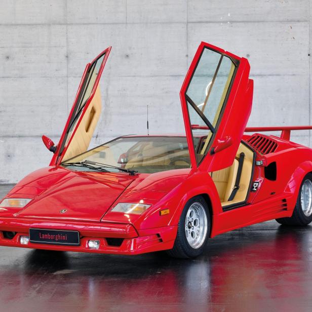 Ein roter Lamborghini Countach mit geöffneten Flügeltüren steht in einem Studio.