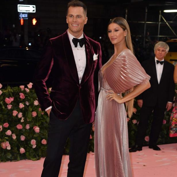Tom Brady und Gisele Bündchen posieren auf einem roten Teppich.