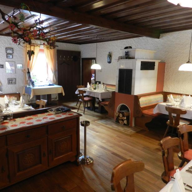 Ein traditionell eingerichtetes Restaurant mit Holzboden und gedeckten Tischen.