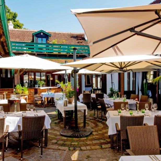 Einladender Außenbereich eines Restaurants mit gedeckten Tischen und Sonnenschirmen.