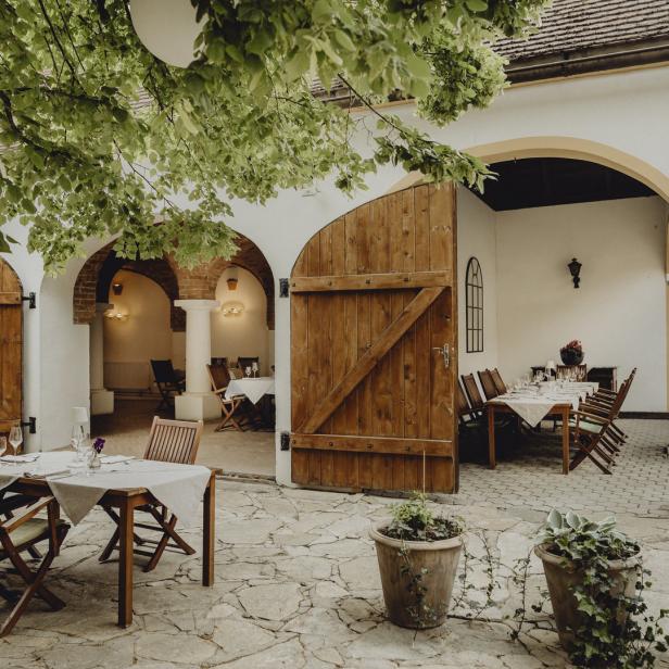Ein Innenhof mit gedeckten Tischen und rustikalen Holztüren.