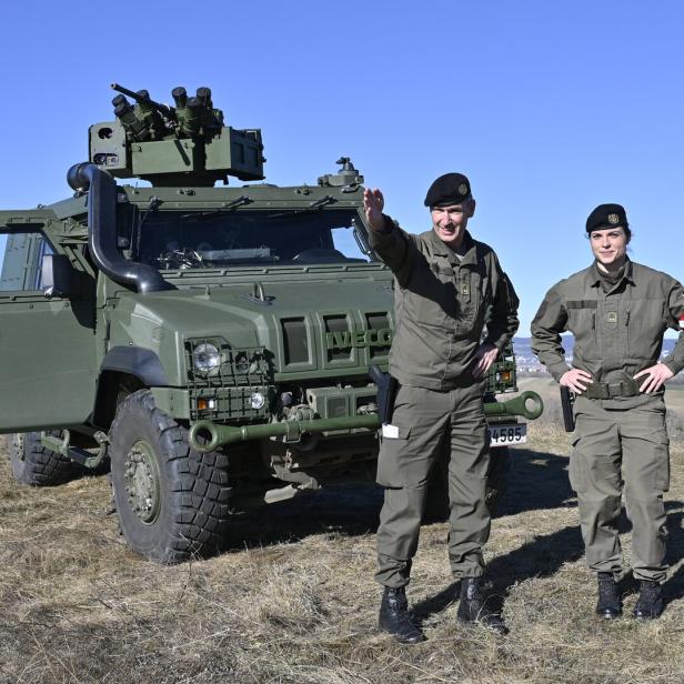 Zwei Soldaten stehen vor einem grünen Militärfahrzeug.