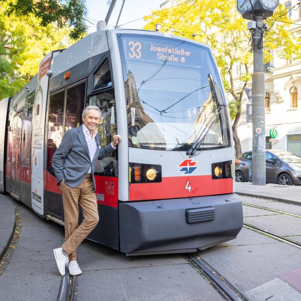 Ein Mann posiert vor einer Straßenbahn der Linie 33 in der Josefstädter Straße, Wien.