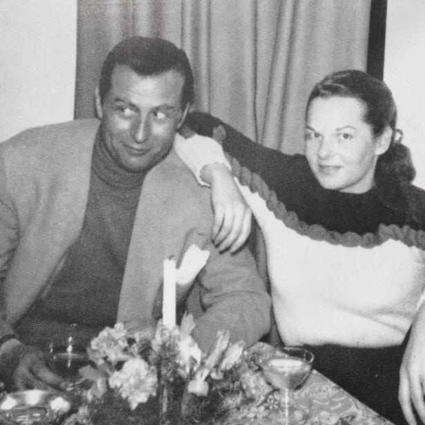 Ein Mann und eine Frau sitzen an einem Tisch mit Blumen und Getränken.