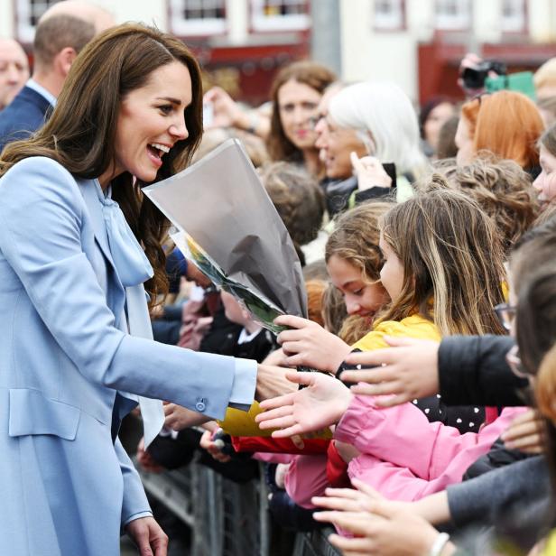 Kate Middleton interagiert mit einer Menschenmenge und nimmt Blumen entgegen.