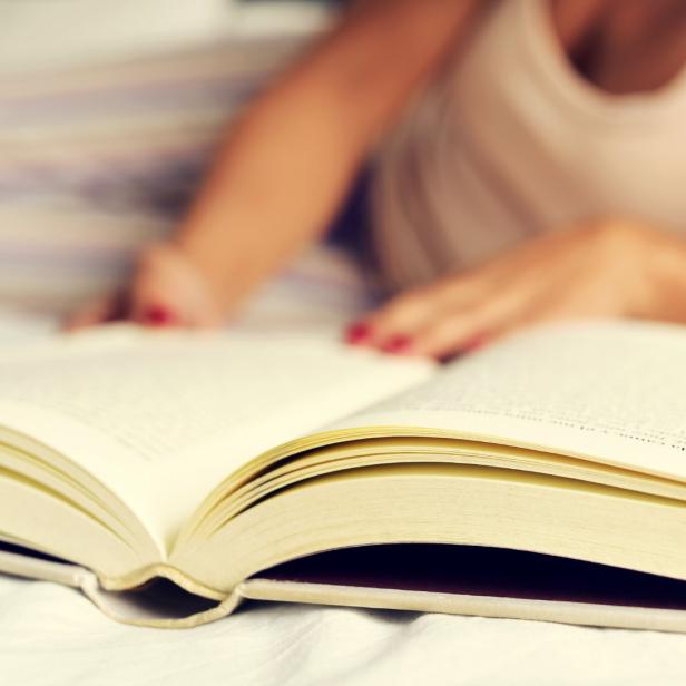 Eine Frau liest ein Buch im Bett.