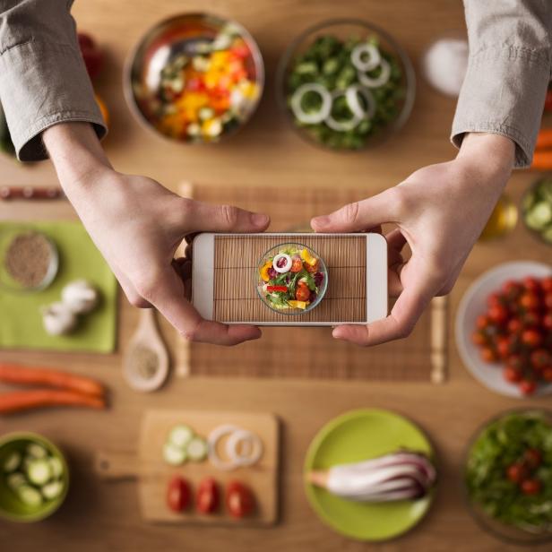 Jemand fotografiert einen bunten Salat mit einem Smartphone.