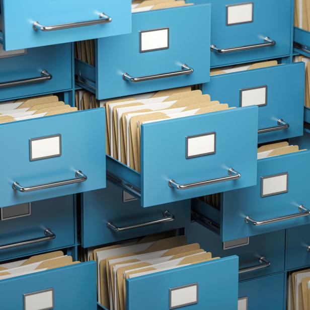 Mehrere geöffnete blaue Aktenschubladen mit zahlreichen sortierten Aktenordnern und leeren Beschriftungsfeldern.