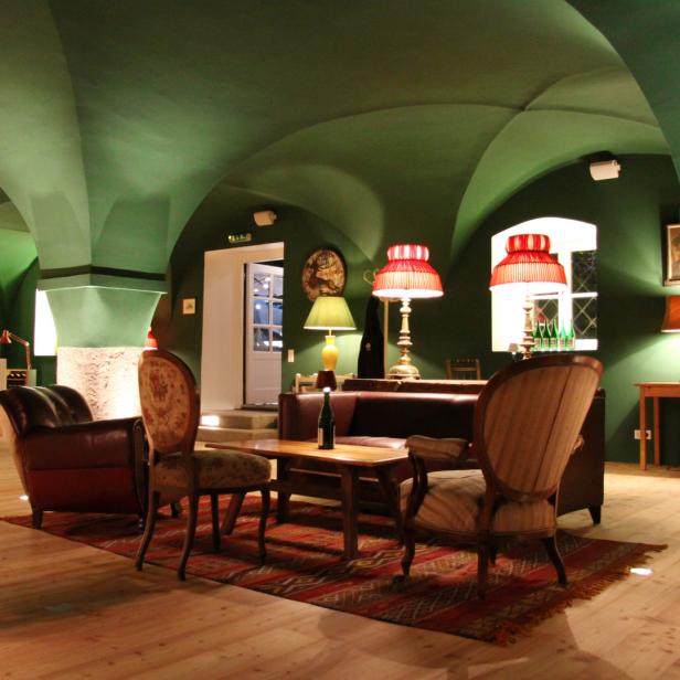 Ein Wohnzimmer mit grünen Wänden und Gewölbedecke, eingerichtet mit antiken Möbeln.