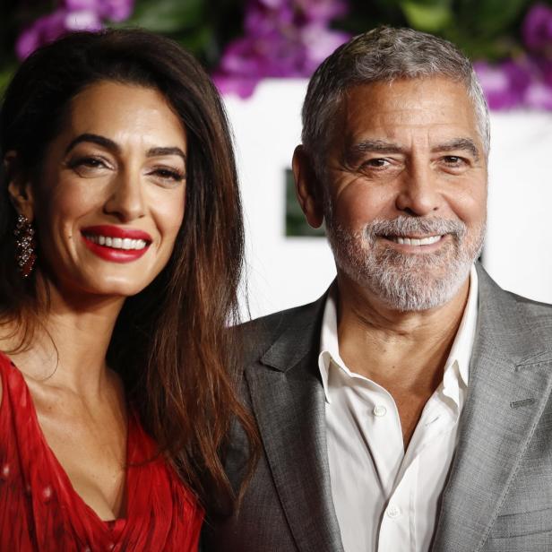 Amal und George Clooney posieren auf einem Event zusammen für ein Foto.