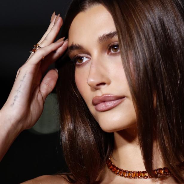 Nahaufnahme von Hailey Biebers Gesicht mit bernsteinfarbenem Schmuck.
