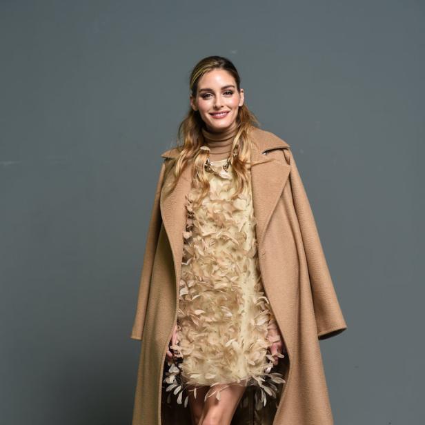 Olivia Palermo trägt einen beigen Mantel und ein Federkleid.