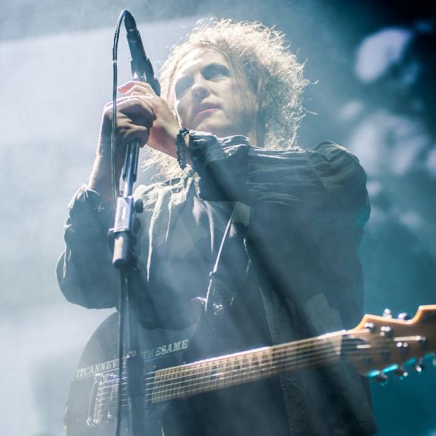 Robert Smith von The Cure singt während eines Konzerts ins Mikrofon.