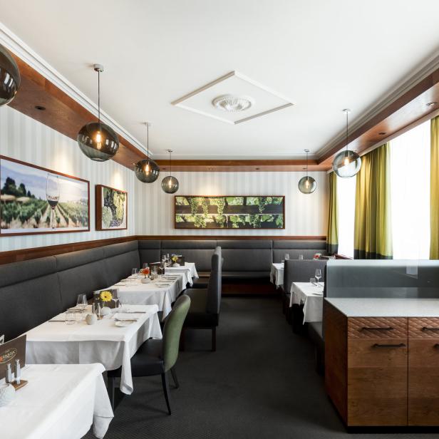 Ein elegantes Restaurant mit gedeckten Tischen und Bildern von Weinbergen an den Wänden.