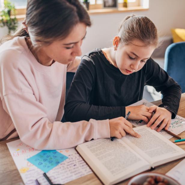 Ein Mädchen lernt mit Hilfe einer jungen Frau für die Schule.