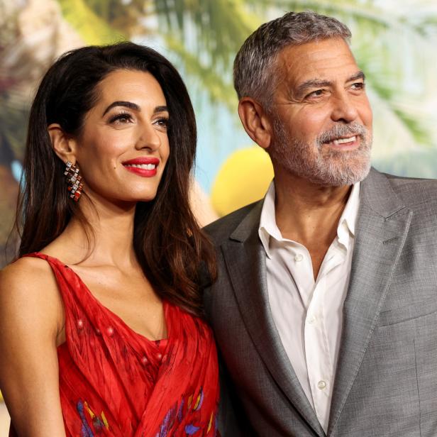 Amal und George Clooney posieren auf einem Event zusammen.