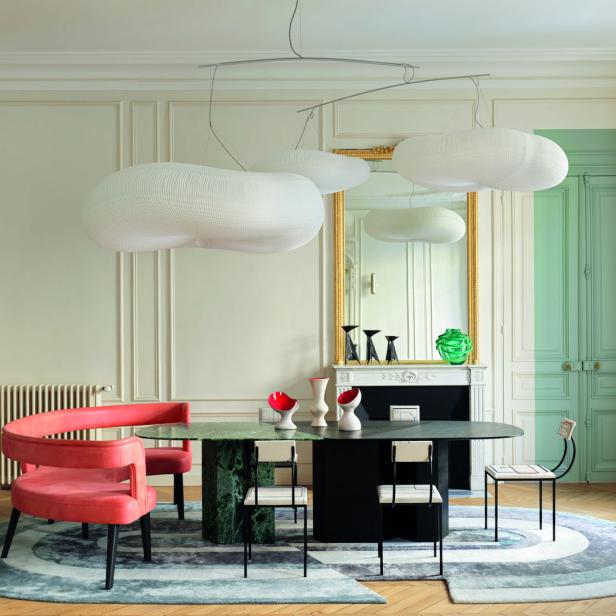 Ein Esszimmer mit einem ovalen Tisch, umgeben von Stühlen und einer skulpturalen Wolkenlampe.