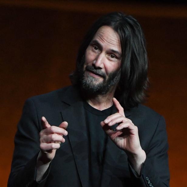 Keanu Reeves gestikuliert während einer Präsentation.
